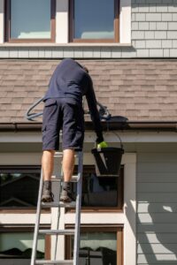 man on a ladder working on gutter cleaning